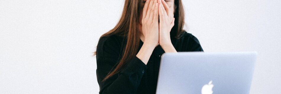 woman with hands on her face in front of a laptop